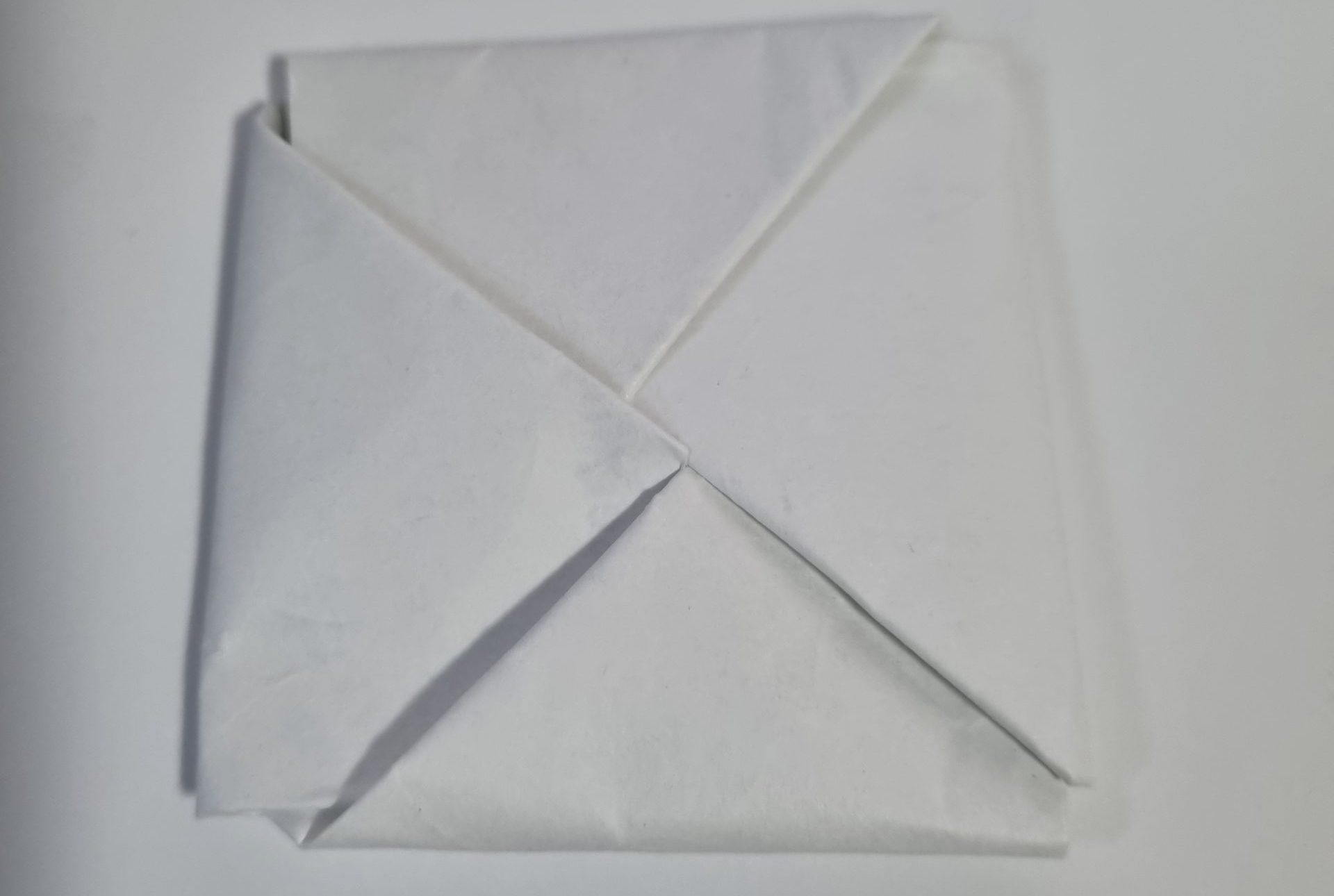 A finished white ddakji paper tile folded from two sheets