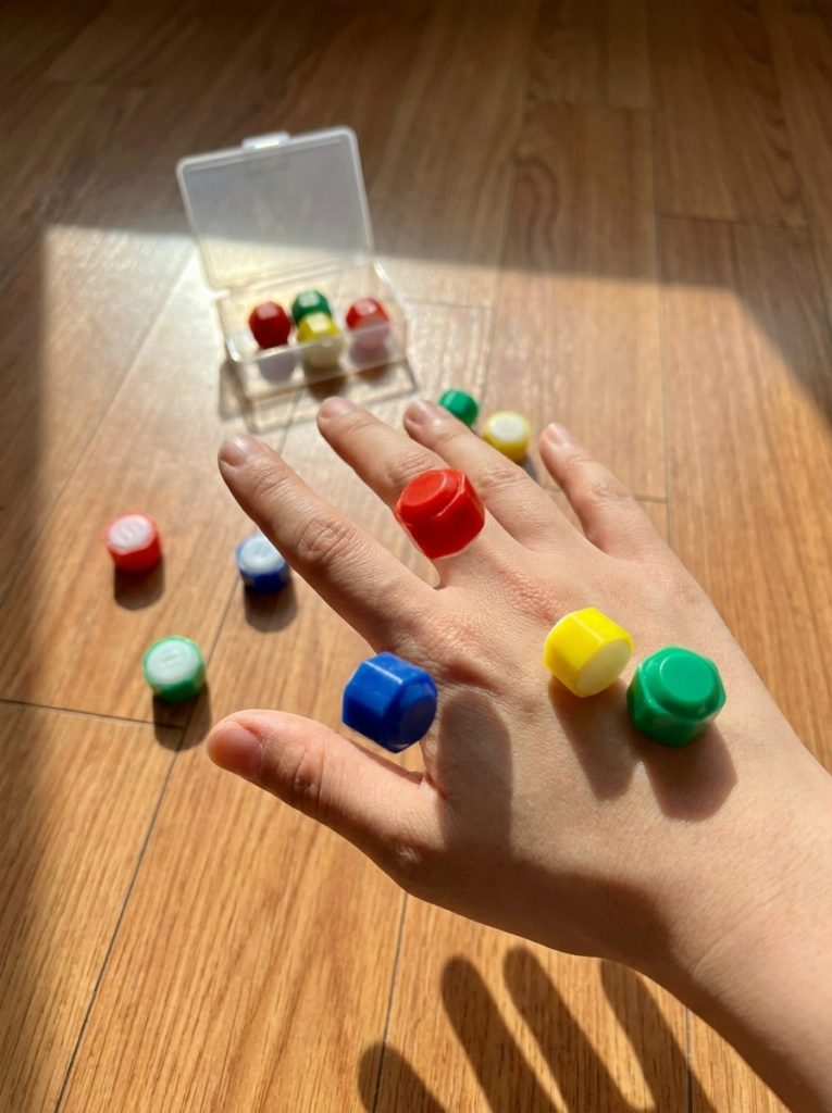 Five small colorful gonggi stones resting on an open palm