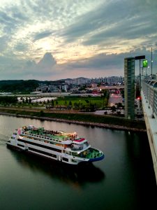 A cruise boat passing along the straight Ara Waterway canal seen from Gyeyang Bridge