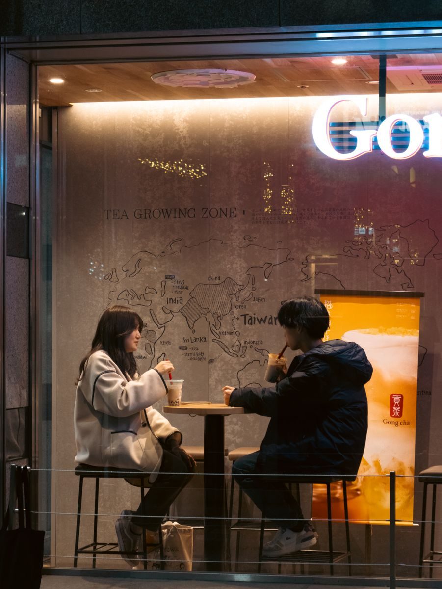 Two people sitting across from each other at a cafe table in conversation