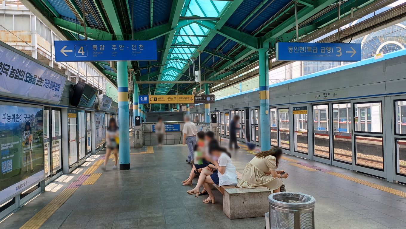 A railway platform at Bupyeong Station with overhead direction signs