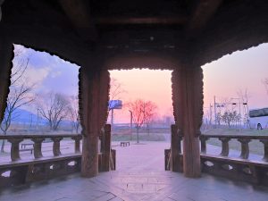 Sunset seen from a traditional wooden pavilion at Duri Ecological Park, with a bicycle resting nearby
