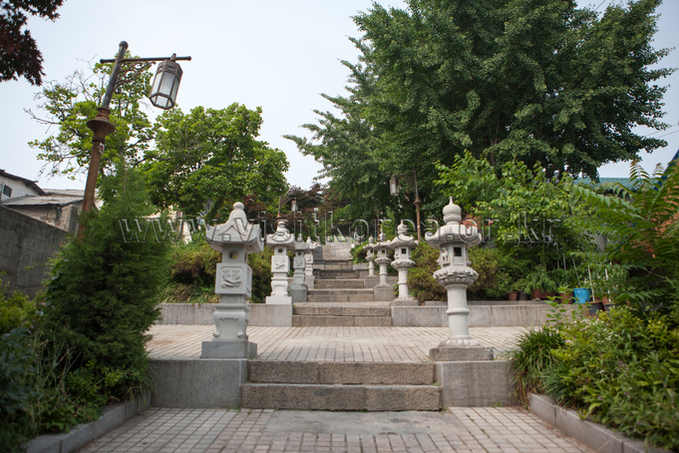 Stone staircase lined with carved stone lanterns and greenery on both sides
