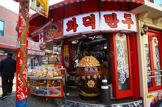Street shop counter with a large clay oven full of baked buns and bagged pastries stacked in front