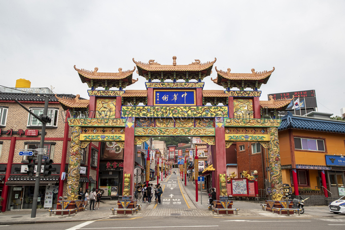 Ornate multi-roofed Chinese gate spanning a street entrance with a blue plaque at its center