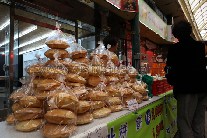 Stacks of bagged flat round pastries piled on a market table