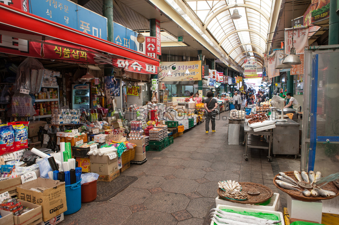 Covered market arcade lined with grocery stalls and dried fish baskets