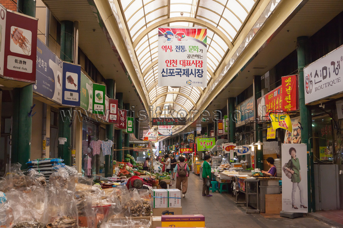 Long covered market street with hanging banners and shops on both sides