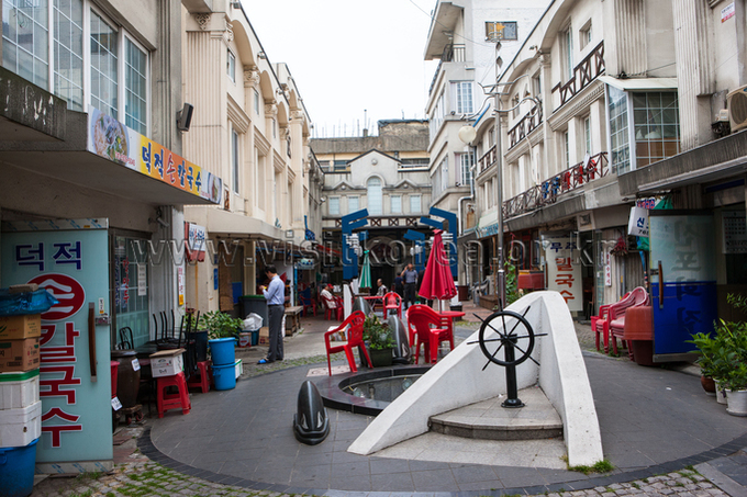Narrow street with early twentieth century buildings and a small plaza