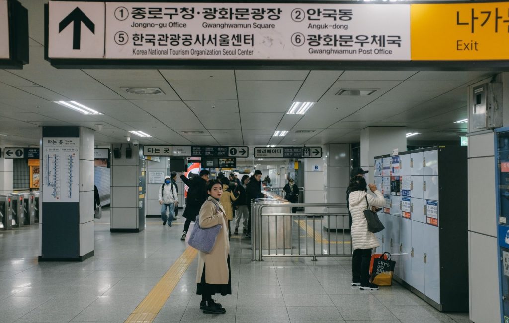 Commuters waiting behind marked floor arrows on a Seoul subway platform