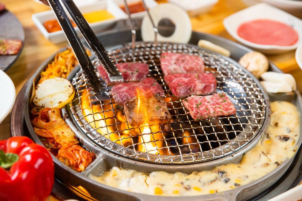 A vibrant Korean BBQ grill with sizzling meats and vegetables cooked over an open flame.