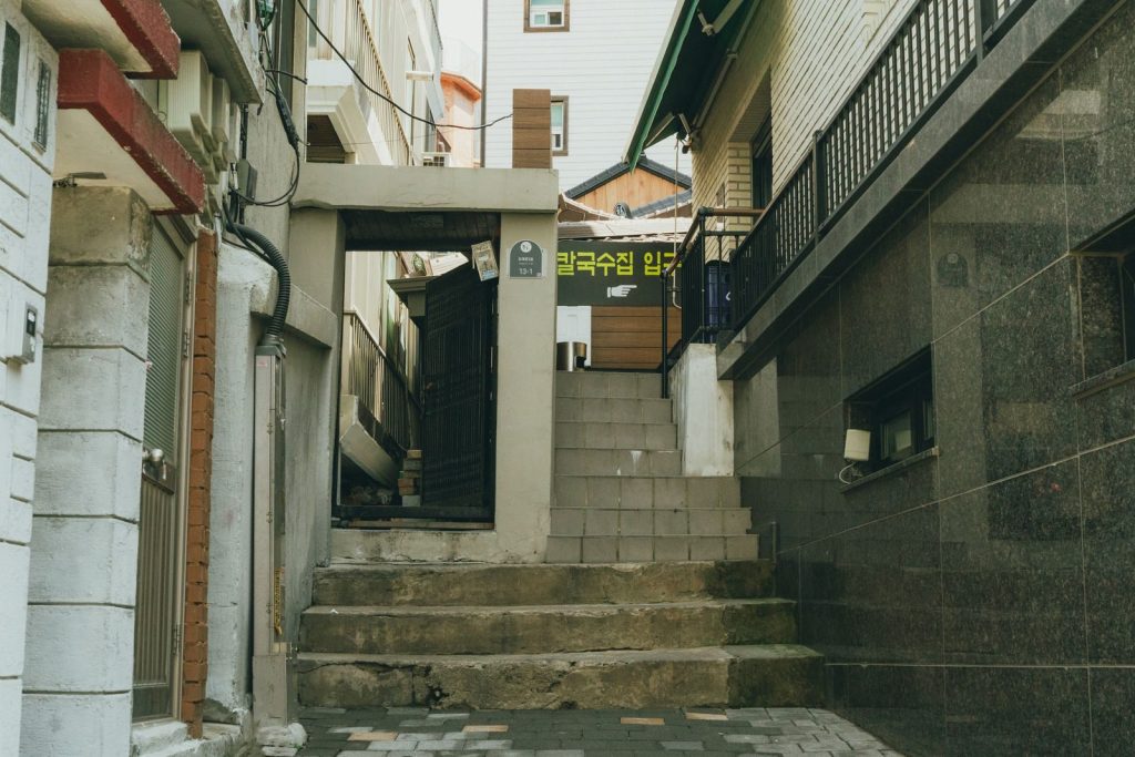 A quiet older residential street with low-rise houses and narrow alleys