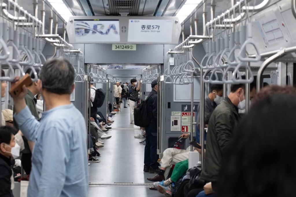 Elderly passenger seated on a Korean subway train during daytime commute