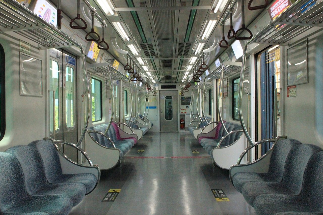 Empty pink-colored priority seats near subway doors with a pregnancy icon on the seatback