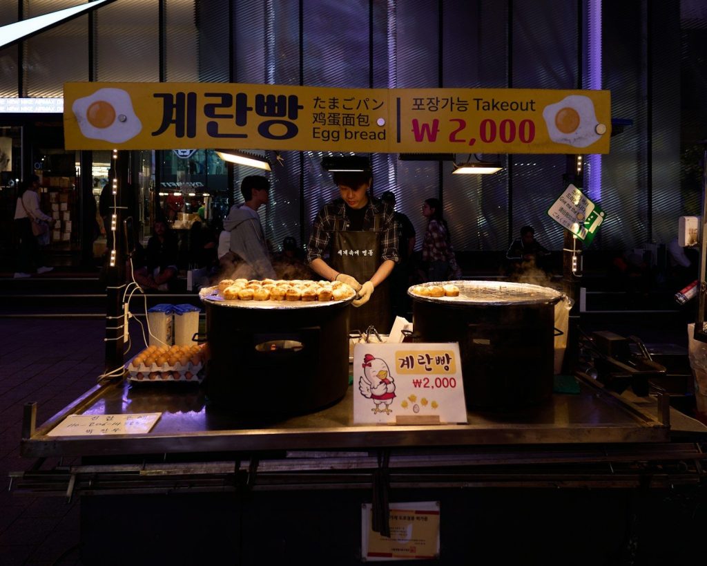 A street food vendor's cart with steam rising on a cold winter evening