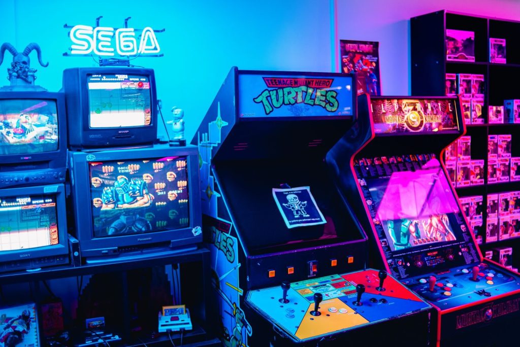 Row of old arcade game cabinets glowing in a dim room