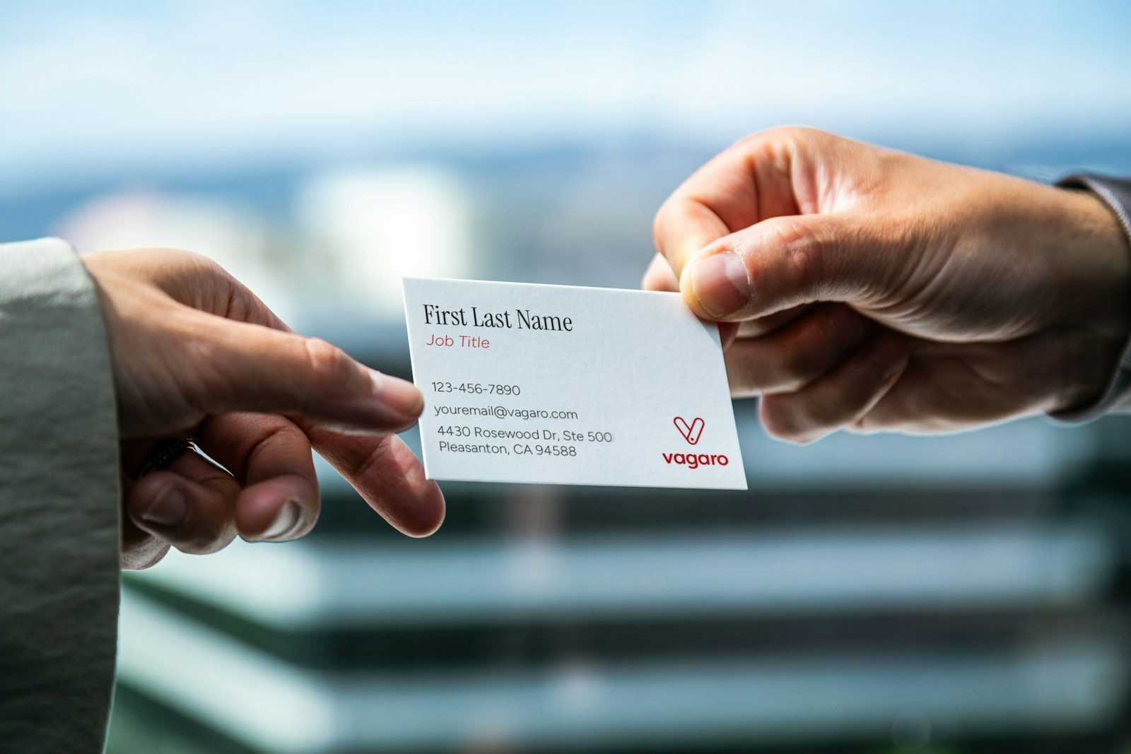 Two people exchanging a business card with both hands at a meeting table