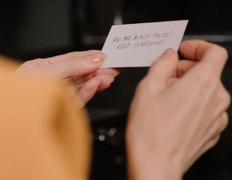 Hands holding a motivational handwritten note in a cozy indoor setting, inspiring perseverance.