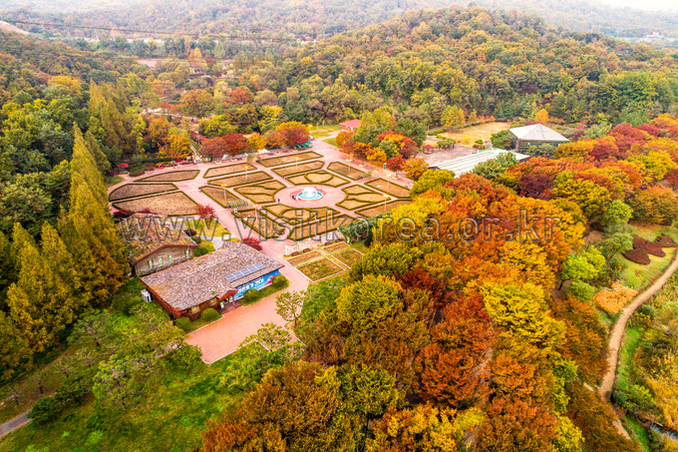 Aerial view of Incheon Grand Park in autumn with a large lake surrounded by colorful trees and low hills