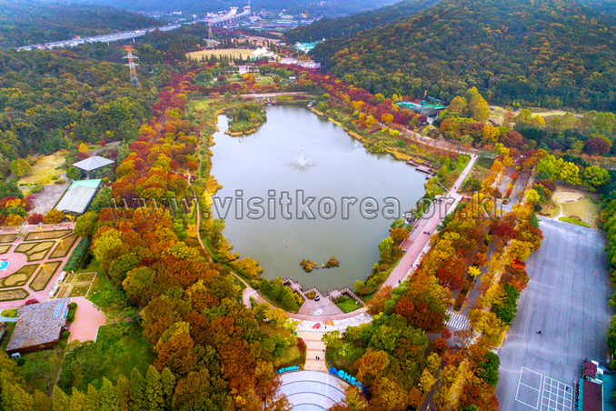 Aerial view of Incheon Grand Park in autumn with a large lake surrounded by colorful trees and low hills