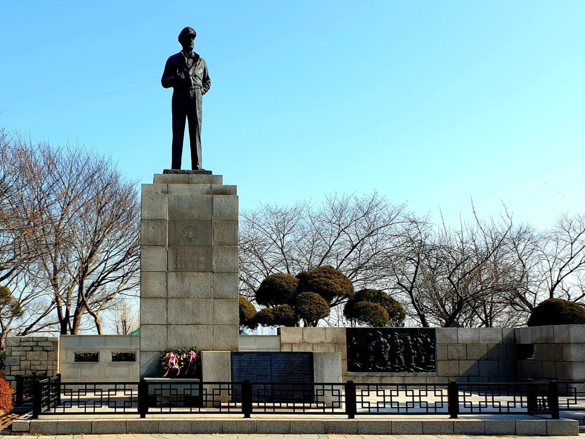 Statue of General MacArthur on a tall stone pedestal in Jayu Park under a clear blue sky