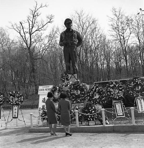 Black-and-white photo from April 1964 showing wreaths laid at the base of the MacArthur statue in Jayu Park