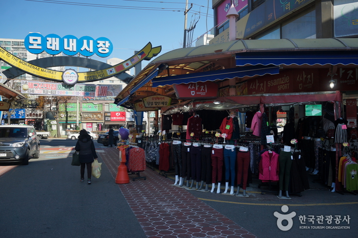 Arched Moraenae Market sign over a street lined with clothing shops in Incheon