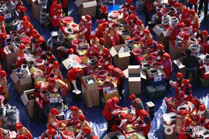 Volunteers in aprons making large amounts of kimchi together at a kimjang sharing event in Korea